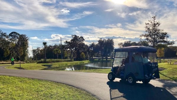 A golf cart and bicyclist share the path between the Village of Bradford and the Village of Chitty Chatty