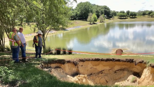 Workers inspect the sinkhole prior to beginning repair of the drainage pipes. They plan on putting a large metal pipe as a sleeve over the damaged pipe Workers inspect the sinkhole prior to beginning repair of the drainage pipes. They plan on putting a large metal pipe as a sleeve over the damaged pipe