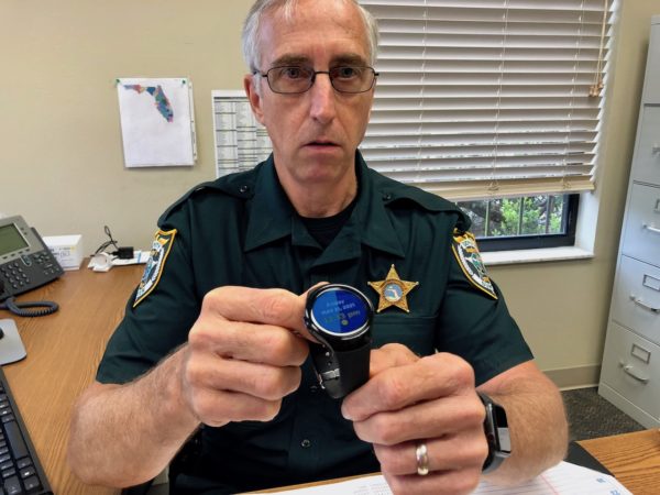 Deputy Marty Egan shows the wrist watch tracker which is part of the DREAM program