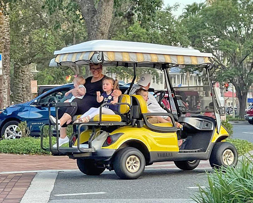 Villagers ride with their grandchildren in a golf cart