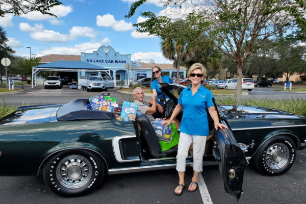 President Julie Schmied and Rotarian Sandra Ricciardi right accept food collected by The Villages Classic Automobile Club.