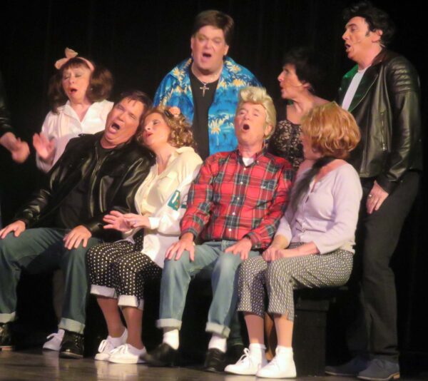 The cast of Grease is decked out in 1950s teen fashions in contrast to Teen Angel