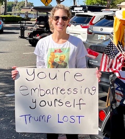 This protester was stationed at Lake Sumter Landing Market Square during the golf cart rally
