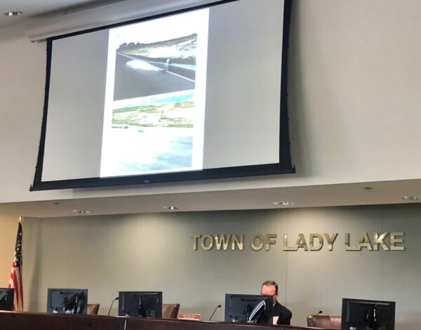 Special Magistrate Joshua Bils seated reviews some of the photos also projected onto the big screen showing erosion at the Lake Ella Estates development