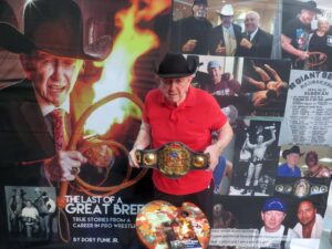 Ocala wrestling hall of famer Dory Funk Jr in front of a poster for his new book The Last of a Great Breed