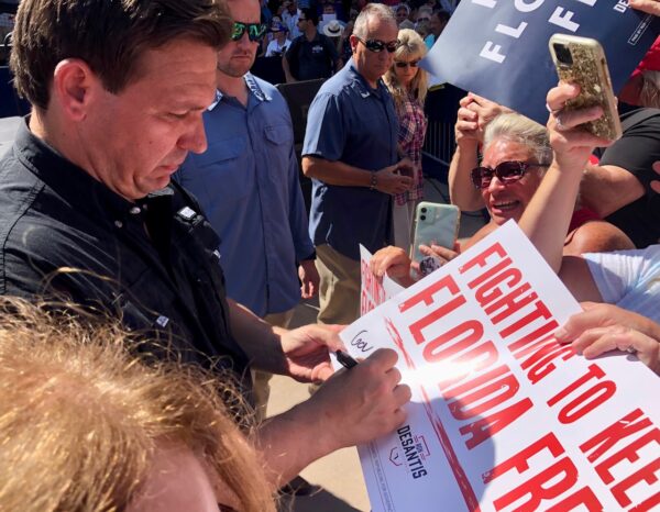 Gov. Ron DeSantis autographs a poster that declares 22Fighting to Keep Florida Free.22 Gov. Ron DeSantis autographs a poster that declares 22Fighting to Keep Florida Free.22