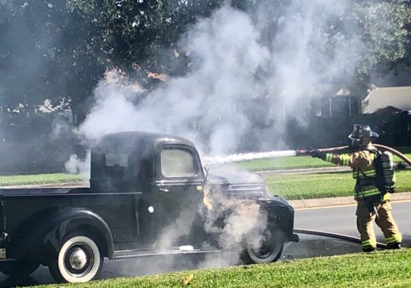 A member of The Villages Public Safety Department used a hose to put out the fire in the engine compartment of the 1947 Ford pickup