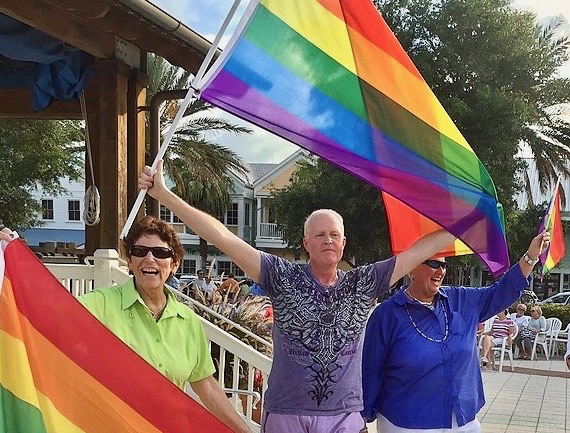 Tim Smith hold the rainbow flag during a celebration at Lake Sumter Landing