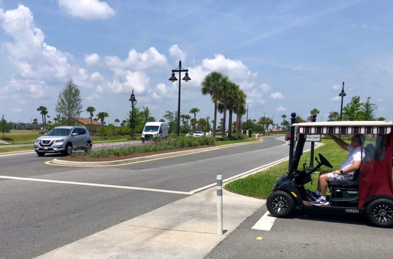 A golf cart prepars to cross Meggison Road