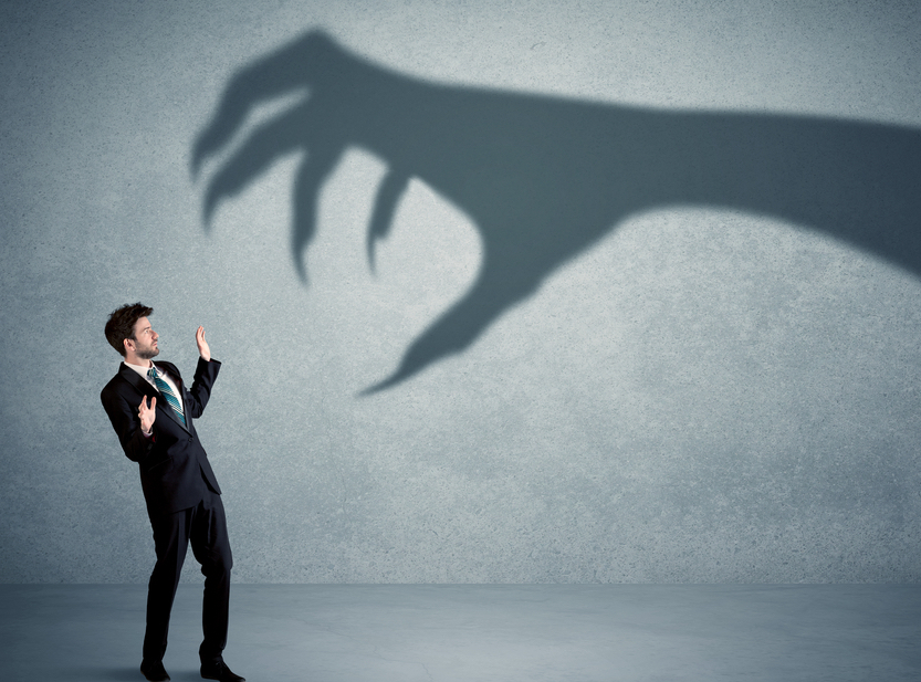 Business person afraid of a big monster claw shadow concept