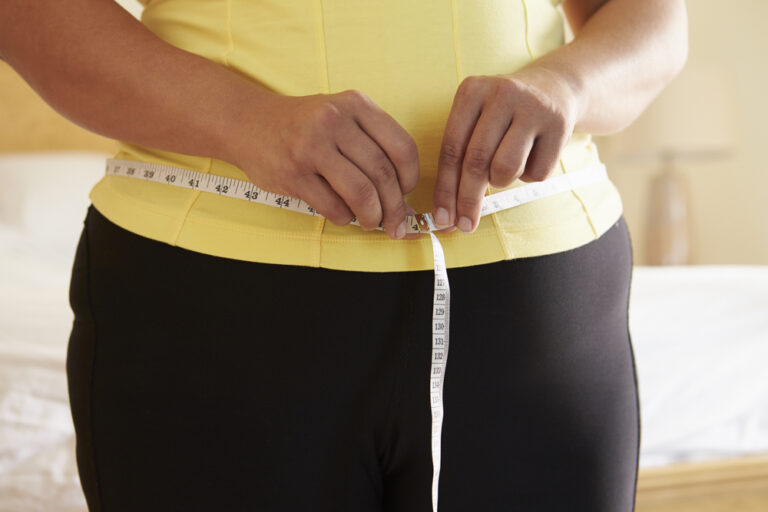 Close Up Of Overweight Woman Measuring Waist