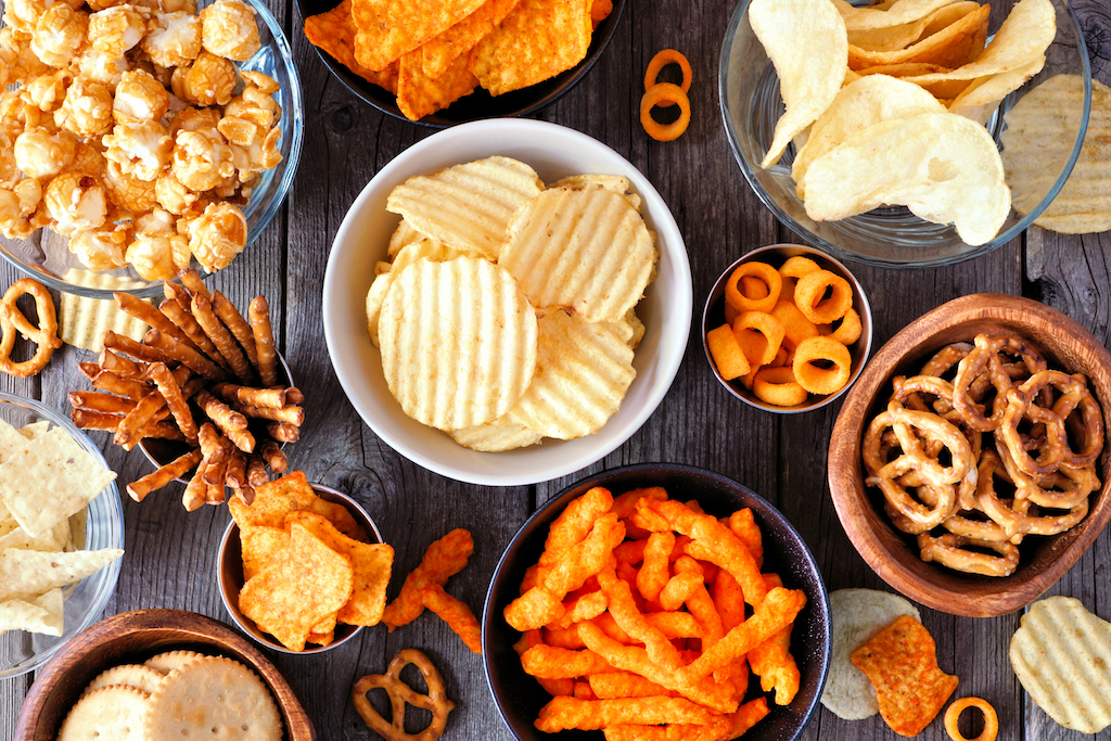 Mixed salty snacks. Flat lay table scene on a rustic wood background.