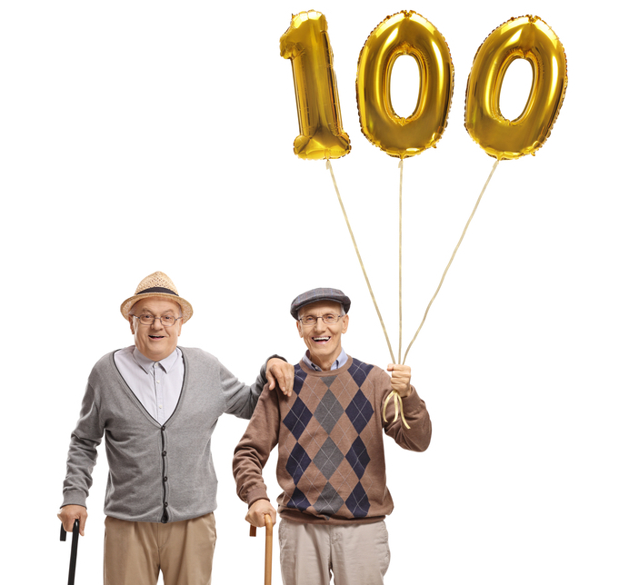 Two senior men with a golden number hundred balloon