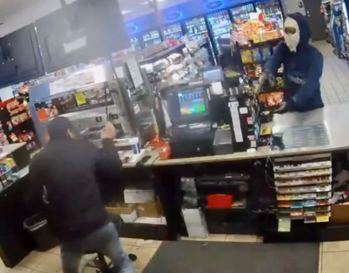 The suspect, at right wearing a ski mask, demanded money from the clerk