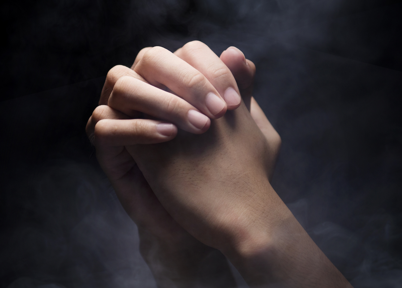 Praying hands over dark background