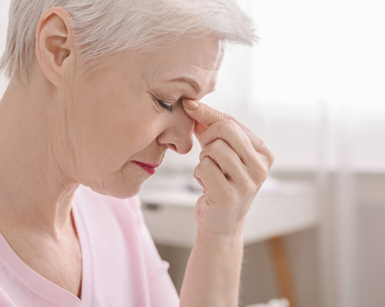 Fatigued senior woman massaging nose bridge, feeling eye strain