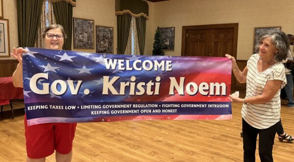 Villagers Arlene Riggs on the right and Sedalia Shute held up a banner welcoming Gov.Noem