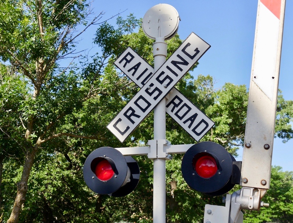 Wide shot of a sign and lights at a railroad crossing