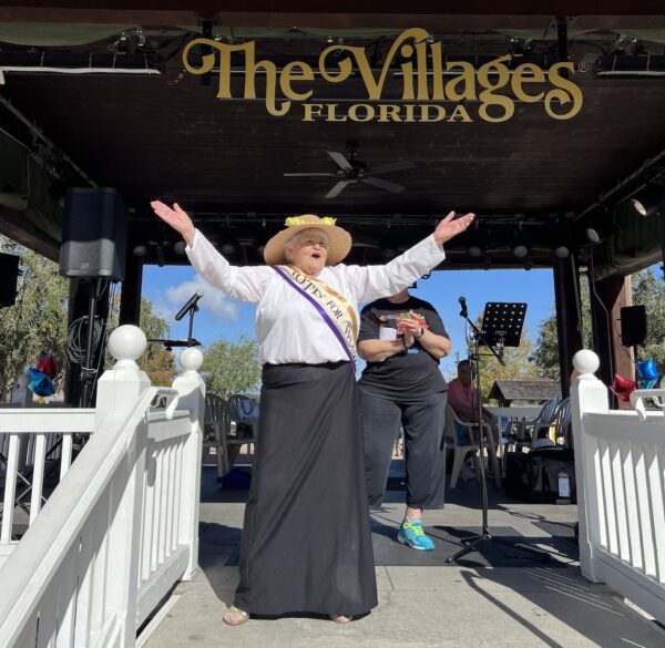 Dorothy Dobbs,dressed as early suffragette addressed the crowd. Dorothy Dobbs, dressed as early suffragette, addressed the crowd from the pavilion at Lake Sumter Landing.
