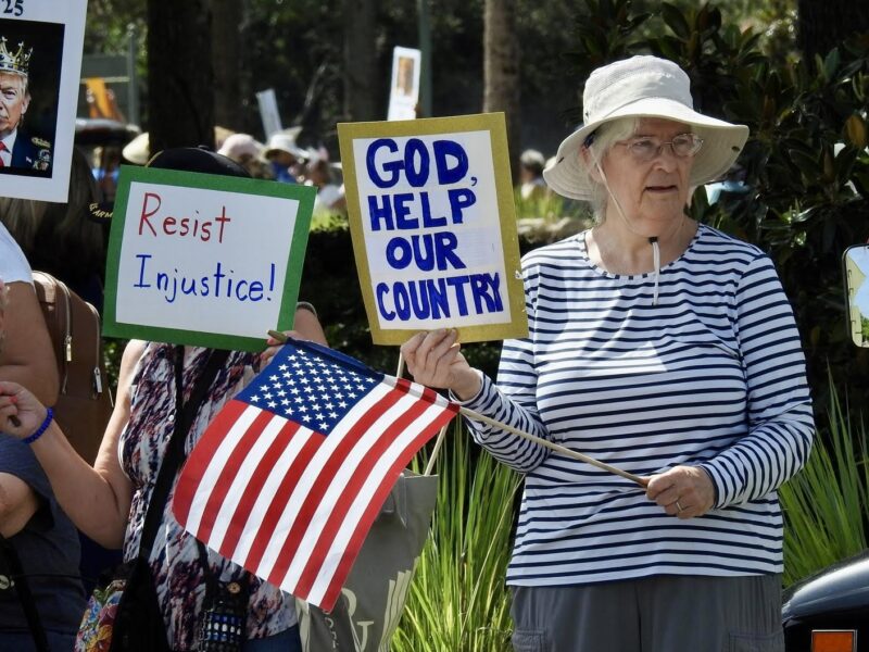 This woman was waving an American flag while she held a sign at the No Kings Rally