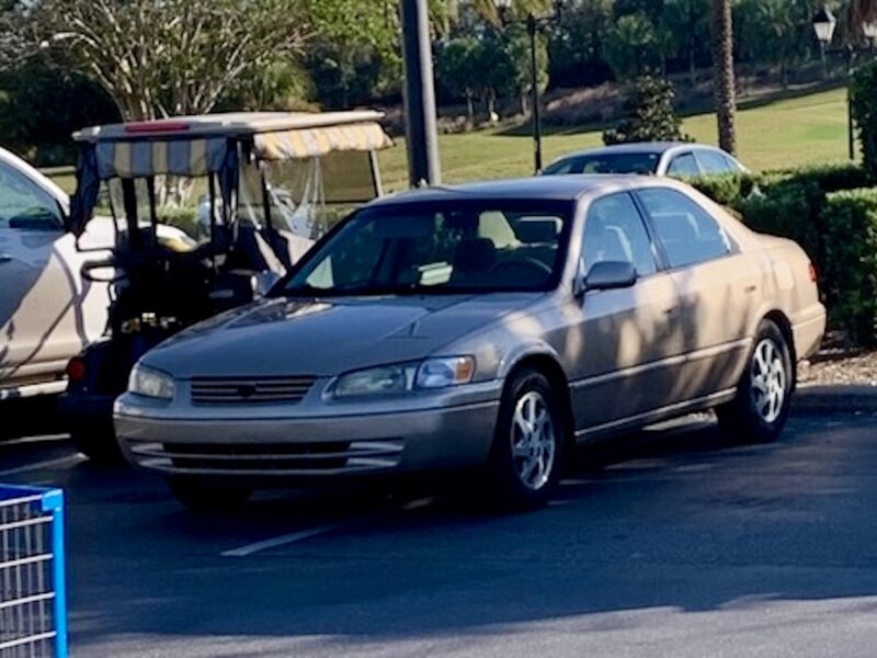 This car was squeezed in alongside a golf cart at Walmart at Sarasota Plaza