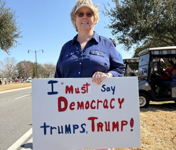 A demonstrator contends that Democracy Trump Trump.