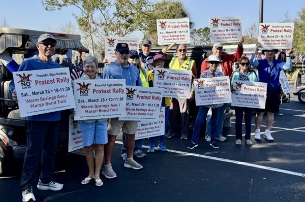 A group holds up signs to promote the upcoming No Kings Rally A group holds up signs to promote the upcoming No Kings Rally