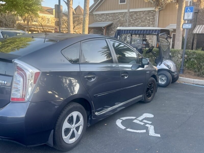 This golf cart squeezed into an occuppied handicapped parking spot
