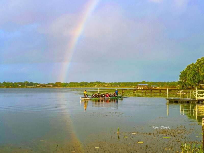 Dragon boaters glide across Lake Miona beneath a rainbow
