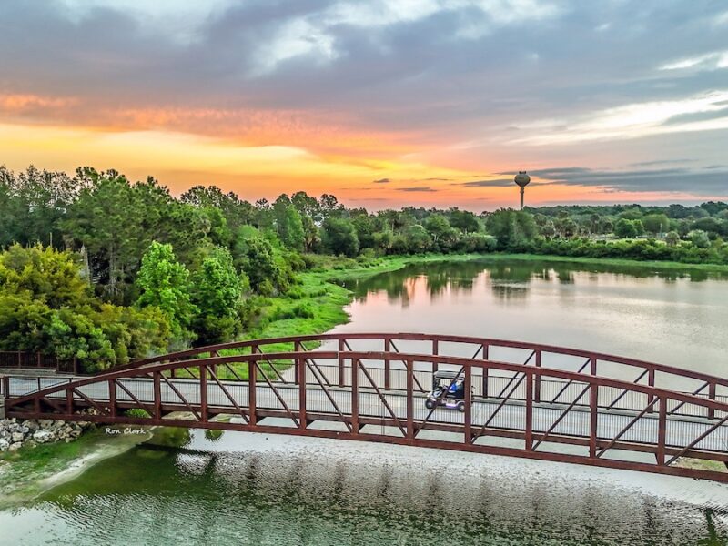 Sunrise paints the sky over golf cart bridge that spans SR 44