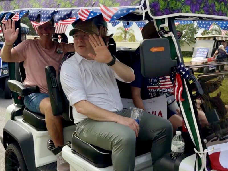 U.S. Senate candidadte Alex Windman waves to the crowd during the golf cart rally