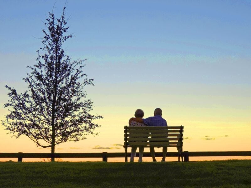 Couple takes in a peaceful sunset from a park bench in The Villages