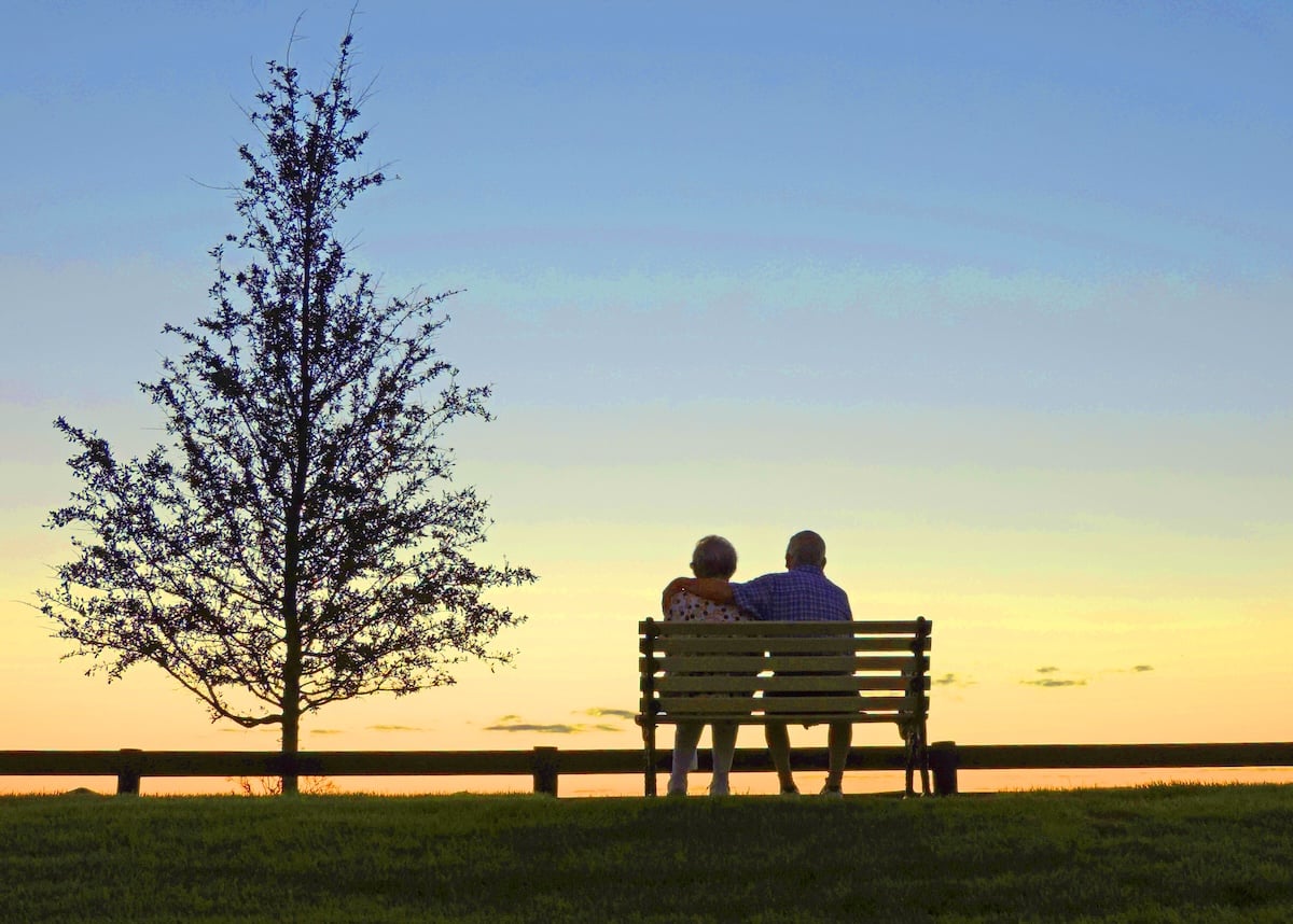 Couple takes in a peaceful sunset from a park bench in The Villages Couple takes in a peaceful sunset from a park bench in The Villages