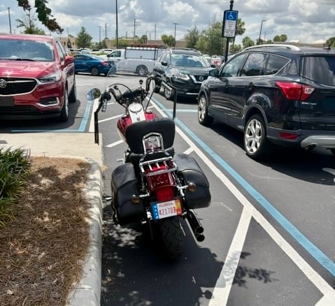 This motorcyclist chose to park in a handicapped accommodation zone This motorcyclist chose to park in a handicapped accommodation zone