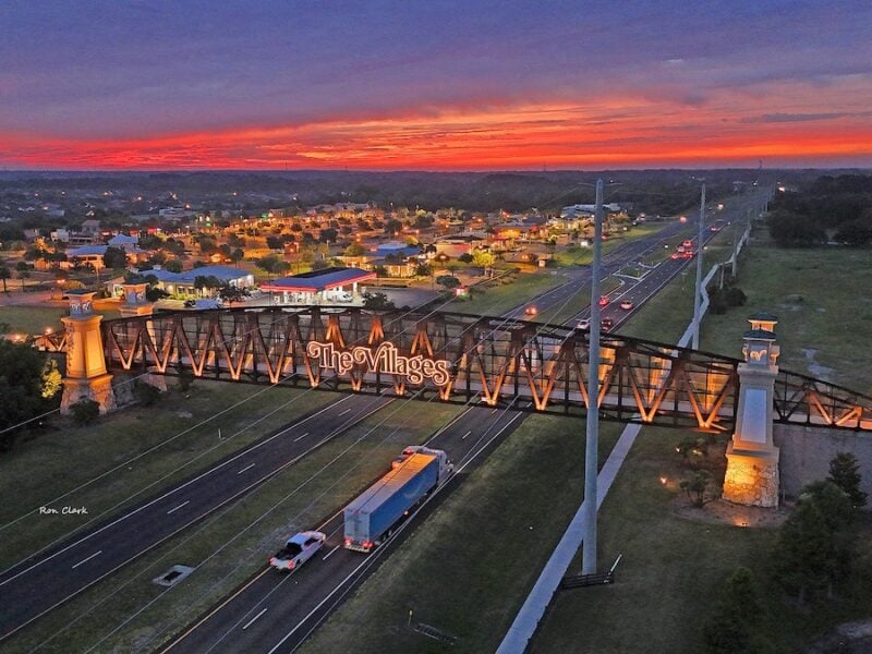 Vibrant sunrise colors the sky over the iconic golf cart bridge at Lake Deaton Plaza